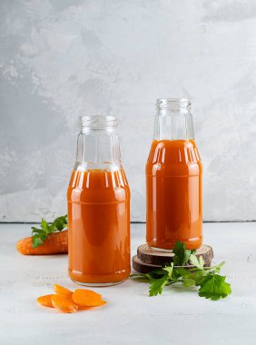 Işık masasında havuç suyu olan iki şişe.