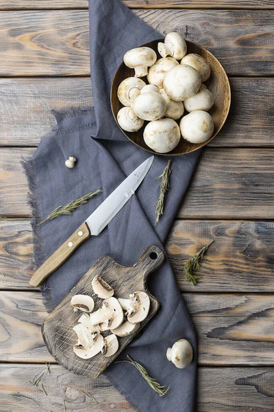 Dilimlenmiş mantarlar koyu kahverengi bir tahta üzerinde yatar.