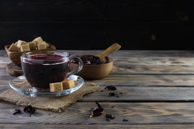 Peçetedeki cam bardakta kırmızı rosella yaprağı çayı.