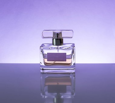 Ayna masasında cam bir şişede güzel kokulu bir parfüm. Açık mor arkaplan. Metin için boşluk