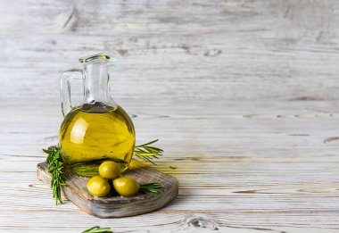 Koyu kahverengi bir tahta üzerinde zeytin yağlı cam sürahi.