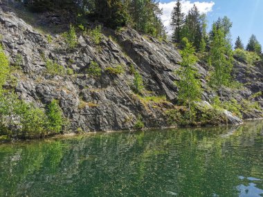 Güneşli bir yaz gününde Ruskeala Dağ Parkı 'ndaki Mermer Kanyon' un kayalık kıyıları ve zümrüt suyu manzarası.