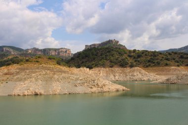 Pantano de Ciurana rezervuarının kayalık kıyısı, dağların arka planına karşı, Tarragona, Katalonya, İspanya.