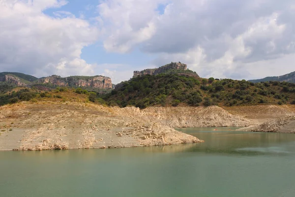 Pantano de Ciurana rezervuarının kayalık kıyısı, dağların arka planına karşı, Tarragona, Katalonya, İspanya.