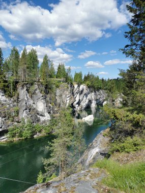 Güneşli bir yaz gününde gökyüzünü ve kayaları yansıtan Ruskeala Dağ Parkı 'ndaki Mermer Kanyon' un kayaları ve zümrüt suyu..