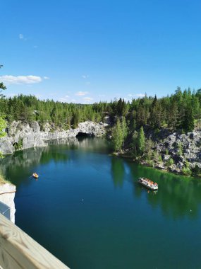 Ruskeala Dağ Parkı 'ndaki Mermer Kanyon' un turkuaz suyunun gözlem güvertesinden gökyüzünün yansıması ve güneşli bir yaz gününde ağaçların görüntüsü..