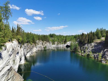 Ruskeala Dağ Parkı 'ndaki Mermer Kanyon' un turkuaz suyunun gözlem güvertesinden gökyüzünün yansıması ve güneşli bir yaz gününde ağaçların görüntüsü..