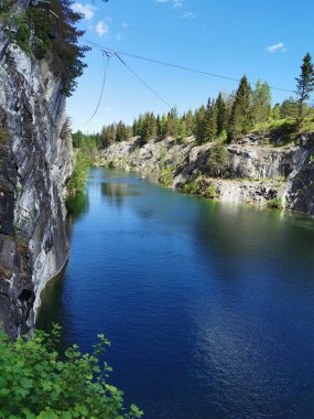 Güneşli bir yaz gününde gökyüzünü ve ağaçları yansıtan Ruskeala Dağ Parkı 'ndaki Mermer Kanyon' un kayaları ve zümrüt suyu..