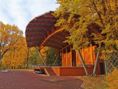 Güneşli bir günde, St. Petersburg Elagin Adası 'ndaki sonbahar parkında ağaçların arasında açık ahşap bir tiyatro..