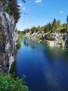 Güneşli bir yaz gününde gökyüzünü ve ağaçları yansıtan Ruskeala Dağ Parkı 'ndaki Mermer Kanyon' un kayaları ve zümrüt suyu..