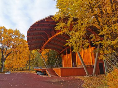 Güneşli bir günde, St. Petersburg Elagin Adası 'ndaki sonbahar parkında ağaçların arasında açık ahşap bir tiyatro..