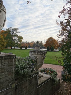  Büyük taş vazolar, arka planda pembe ve mavi çiçekler olan çiçek yatakları ve St. Petersburg 'daki Elagin Adası' ndaki parkta bulutlu gökyüzü..