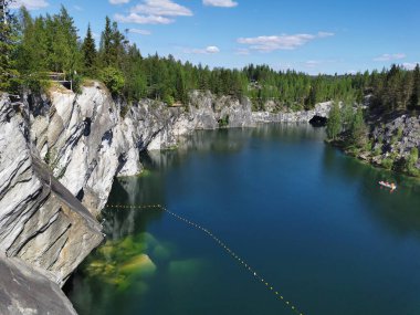 Bir yaz günü Ruskeala Dağ Parkı 'ndaki Mermer Kanyon' un turkuaz sularında yüzen kayalıkların, mağaraların ve teknelerin en üst görüntüsü..