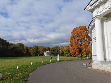 Petrol çayırı arasındaki yol, güzel bir fener, turuncu yapraklı bir ağaç ve St. Petersburg 'daki Elagin Adası' ndaki bulutlu mavi gökyüzü üzerinde bir çadır.