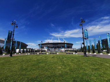 EURO 2020 Avrupa Futbol Şampiyonası 'nın olduğu sabah St. Petersburg' daki Gazprom Arena Stadyumu 'nun önündeki çimen ve banklar bulutlu mavi gökyüzüne karşı..