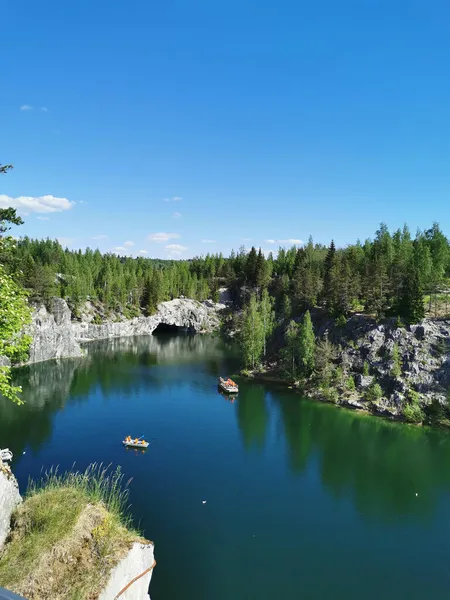 Ruskeala Dağ Parkı 'ndaki Mermer Kanyon' un turkuaz suyunun gözlem güvertesinden gökyüzünün yansıması ve güneşli bir yaz gününde ağaçların görüntüsü..