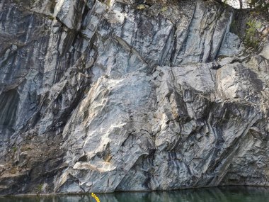 Güneşli bir yaz gününde Ruskeala Dağ Parkı 'ndaki su basmış Mermer Kanyon' un dik yamacındaki sudan manzara.