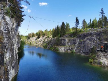Güneşli bir yaz gününde Ruskeala Dağ Parkı 'ndaki Mermer Kanyon' un turkuaz sularında yüzen kayalıkları, halatı ve botları görmek..