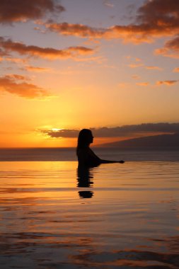 10 YIL ÖNCE İSPAN. Profildeki bir kız güzel bir gün batımının ve okyanusun arka planında havuzda duruyor. Otel 