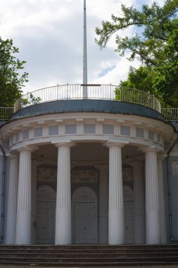 Bayrağın altında beyaz sütunlu bir kubbe ile süslenmiş Mavi Pavilion..