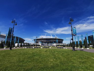 EURO 2020 Avrupa Futbol Şampiyonası 'nın olduğu sabah St. Petersburg' daki Gazprom Arena Stadyumu 'nun önündeki çimen ve banklar bulutlu mavi gökyüzüne karşı..