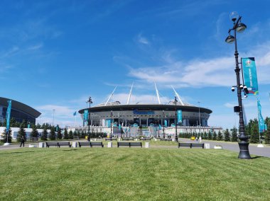 EURO 2020 Avrupa Futbol Şampiyonası 'nın olduğu sabah St. Petersburg' daki Gazprom Arena Stadyumu 'nun önündeki çimen ve banklar bulutlu mavi gökyüzüne karşı..