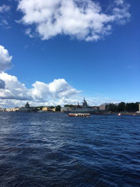 Warships in the water area of the Neva, arrived to participate in the naval parade in St. Petersburg, near pleasure boats with tourists.