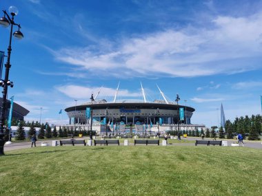 EURO 2020 Avrupa Futbol Şampiyonası 'nın olduğu sabah St. Petersburg' daki Gazprom Arena Stadyumu 'nun önündeki çimen ve banklar bulutlu mavi gökyüzüne karşı..