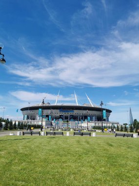 EURO 2020 Avrupa Futbol Şampiyonası 'nın olduğu sabah St. Petersburg' daki Gazprom Arena Stadyumu 'nun önündeki çimen ve banklar bulutlu mavi gökyüzüne karşı..