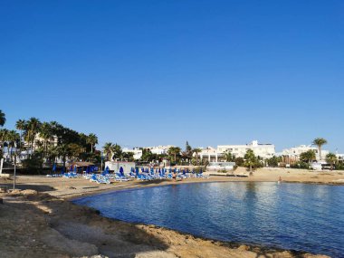 Protaras. Kıbrıs, Akdeniz kıyıları, taştan bir tepe, sonunda balıkçı, denizde bulutlu mavi bir gökyüzüne karşı beyaz bir zevk yatı..