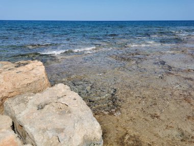 Protaras. Famagusta bölgesi. Kıbrıs. Akdeniz kıyılarında büyük taşlar, berrak deniz suyu ve bulutsuz bir gökyüzü..