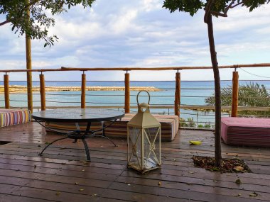 Protaras. Kıbrıs Akdeniz 'in körfezinde kumlu bir sahil güneşin altında Aziz Nicholas Kilisesi dramatik bir gökyüzü ve denizin üzerinde yağmur, denizde bir gemi..