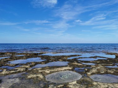 Protaras. Famagusta bölgesi. Kıbrıs. Uzun sert lavlar, Akdeniz kıyıları beyaz bir yatı ve güzel bulutları olan mavi bir gökyüzü olan denizin arka planına karşı..