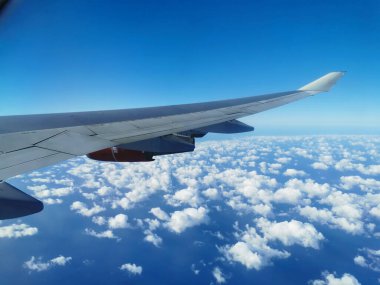 Sabahleyin güzel beyaz bulutların ve Akdeniz 'in üzerinde uçan kırmızı bir uçak motoruyla bir uçağın kanadındaki lompadan manzarayı izleyeceğiz..