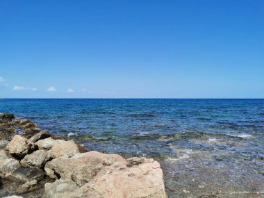 Protaras. Famagusta bölgesi. Kıbrıs. Akdeniz kıyıları, dalgalar, berrak su, bulutlu mavi gökyüzüne karşı taş bir sırt..