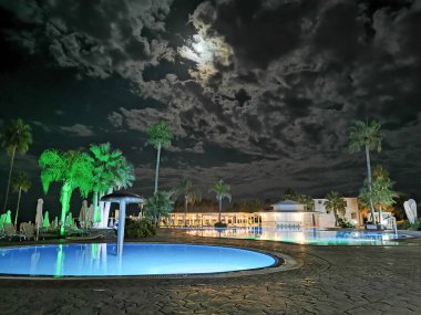 Protaras.Cyprus. Akdeniz sahilinde büyük bir yüzme havuzu, palmiye ağaçları ve mavi bir gökyüzüne karşı..