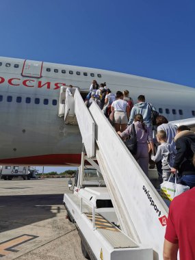 Güneşli bir günde Paphos 'taki Kıbrıs havaalanından çift katlı Rossiya Havayolları uçağına binen yolcular.