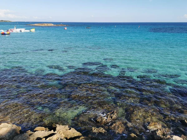 Protaras. Famagusta bölgesi. Kıbrıs. Akdeniz 'in berrak sularını, İncir Ağacı Koyu sahilindeki iskeleyi bir tekne, katamaranlar ve adanın olduğu