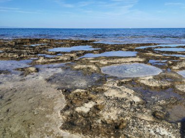 Protaras. Famagusta bölgesi. Kıbrıs. Uzun sert lavlar, Akdeniz kıyıları beyaz bir yatı ve güzel bulutları olan mavi bir gökyüzü olan denizin arka planına karşı..