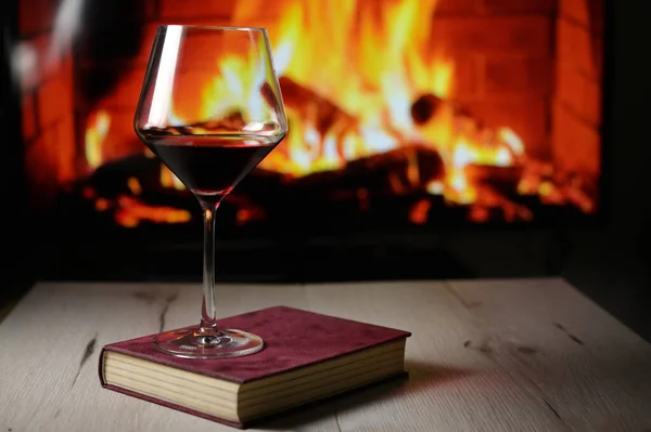 Trockenes Glas Rotwein Auf Buch Und Kamin Hintergrund lizenzfreie Stockbilder