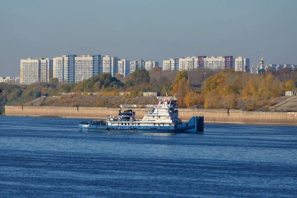 Un remolcador, un barco empujando va a lo largo del río, un panorama de la ciudad. —  Fotos de Stock