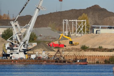 Nehir kıyısındaki inşaat alanında. Su kaynaklarının çıkarılması ve taşınması, nehir kumu. İskele vinci mavnaya nehir kumu yüklüyor. - Evet. Yüksek kalite fotoğraf