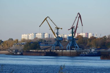 Nehir limanı. Nehir kıyısındaki inşaat alanında. Bir liman vinci bir mavnaya kum yüklüyor. Yüksek kalite fotoğraf
