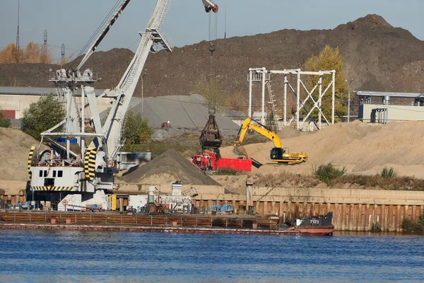 Construction site on the river bank. Extraction and transportation of water resources, river sand. The port crane loads river sand into the barge. . High quality photo