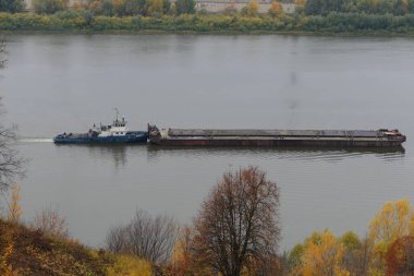 Bir römorkör sonbaharda nehirde bir mavna taşır. Nizhny Novgorod, Oka Nehri. Yüksek kalite fotoğraf