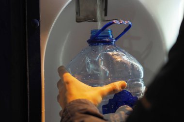 Bir insan, sokağa kurulmuş bir cihazdan temiz içme suyu topluyor. Artesian içme suyu için. - Evet. Yüksek kalite fotoğraf