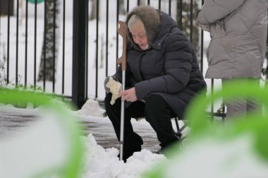 Nizhny Novgorod, Rusya, Prioksky bölgesi St. Tropinin 11.14.2021. Engelli yaşlı bir kadın kışın parkta yüksek bir sandalyede dinlenir. Yüksek kalite fotoğraf