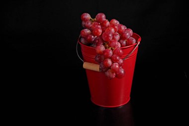 Hayat, kırmızı kovada siyah arka planda kırmızı büyük üzümler. - Evet. Yüksek kalite fotoğraf