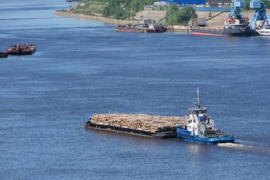 A barge unloaded with large logs goes along the river in summer. High quality photo clipart