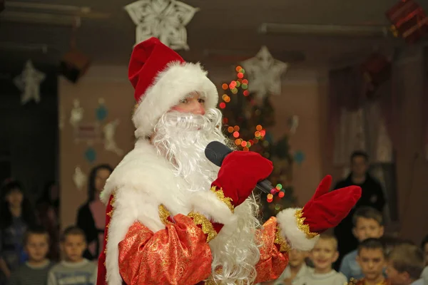 Yeni yıl. Kırmızı elbiseli Noel Baba, anaokulundaki bir matinede çocuklarla oynuyor..